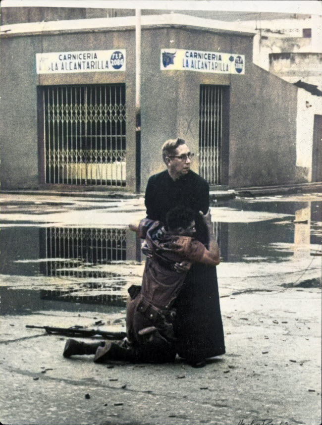 صورة مساعدة الأب التى يظهر فيها أحد رجال الدين أثناء محاولته إنقاذ أحد الجنود المصابين فى فنزويلا