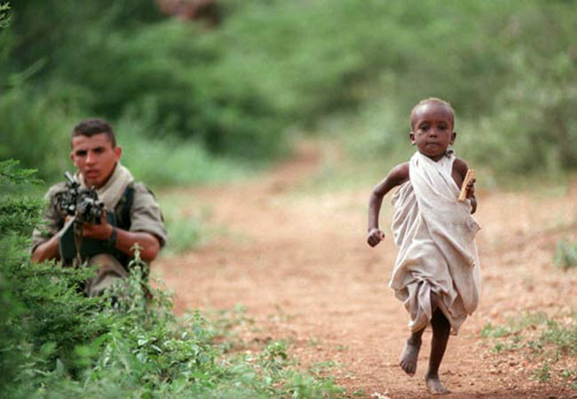 صورة جري صبي صومالي نحو إحدي قوافل الإغاثة و خلفه جندي فرنسي يؤمنها بسلاحه