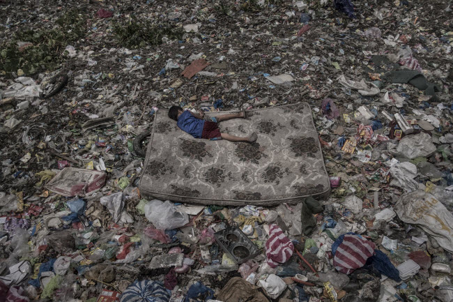 صورة طفل فلبيني نائم علي مرتبة فوق أطنان من القمامة ملقاة علي نهر باسيج